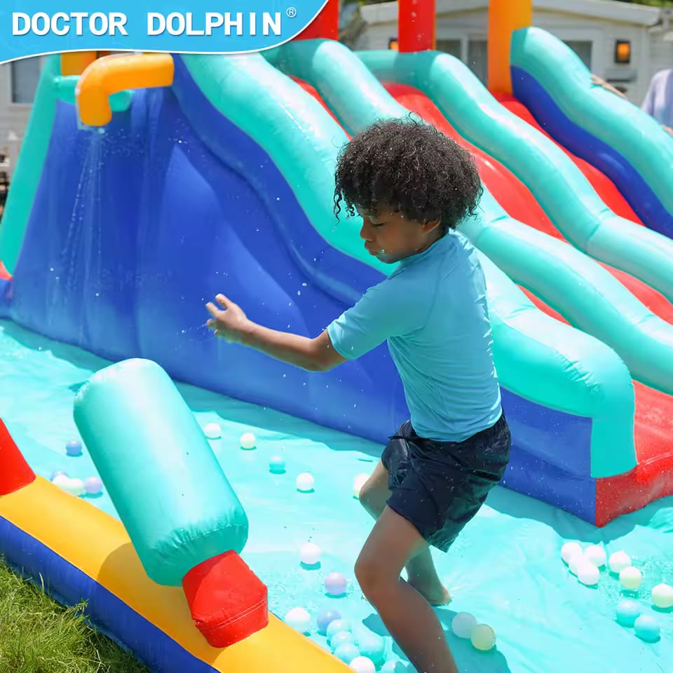 Child playing on a colorful inflatable water slide with 'Doctor Dolphin' branding.